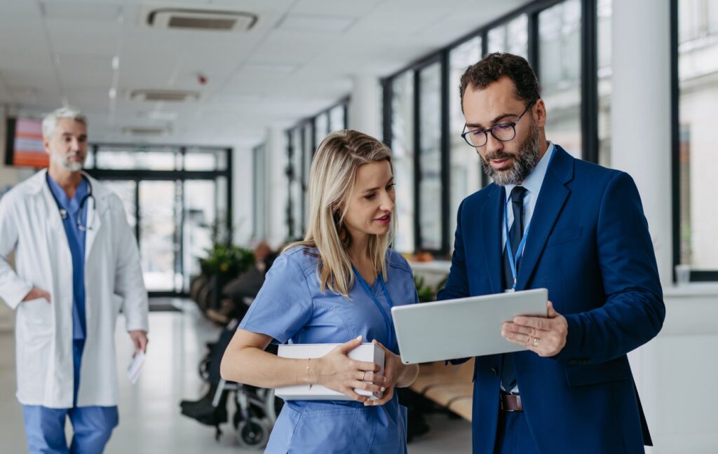 Medical professionals discussing using laptop in hospital corridor - trualign healthcare partners